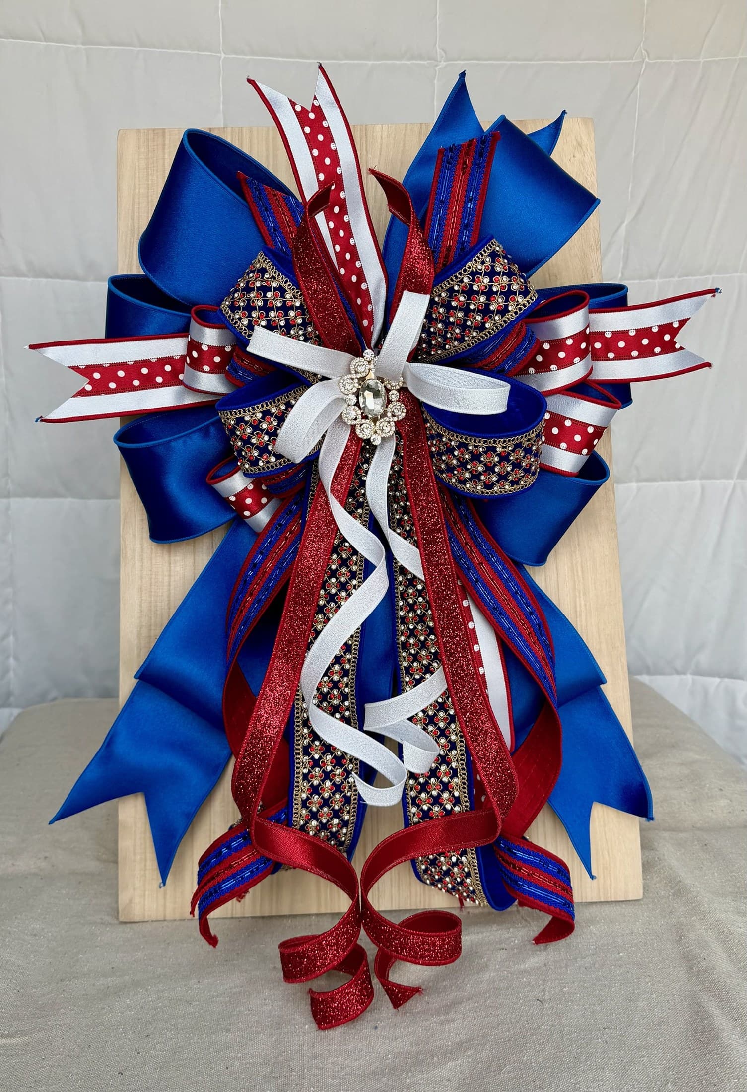 Close-up of a patriotic bow with red ribbon, blue ribbon, white accents, and ornaments.