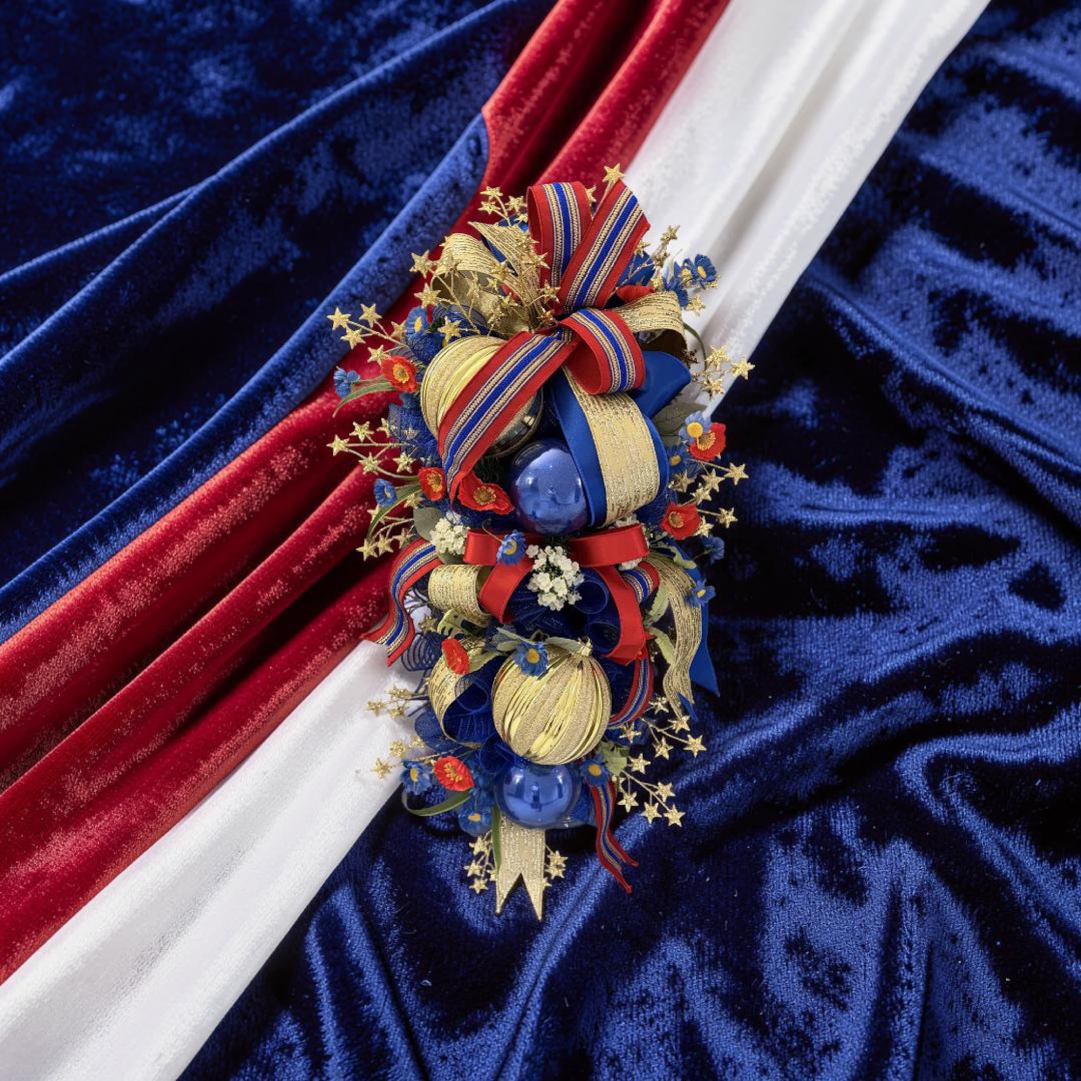 Close-up of patriotic ribbon, ornaments, and textured fabric in a custom holiday swag.