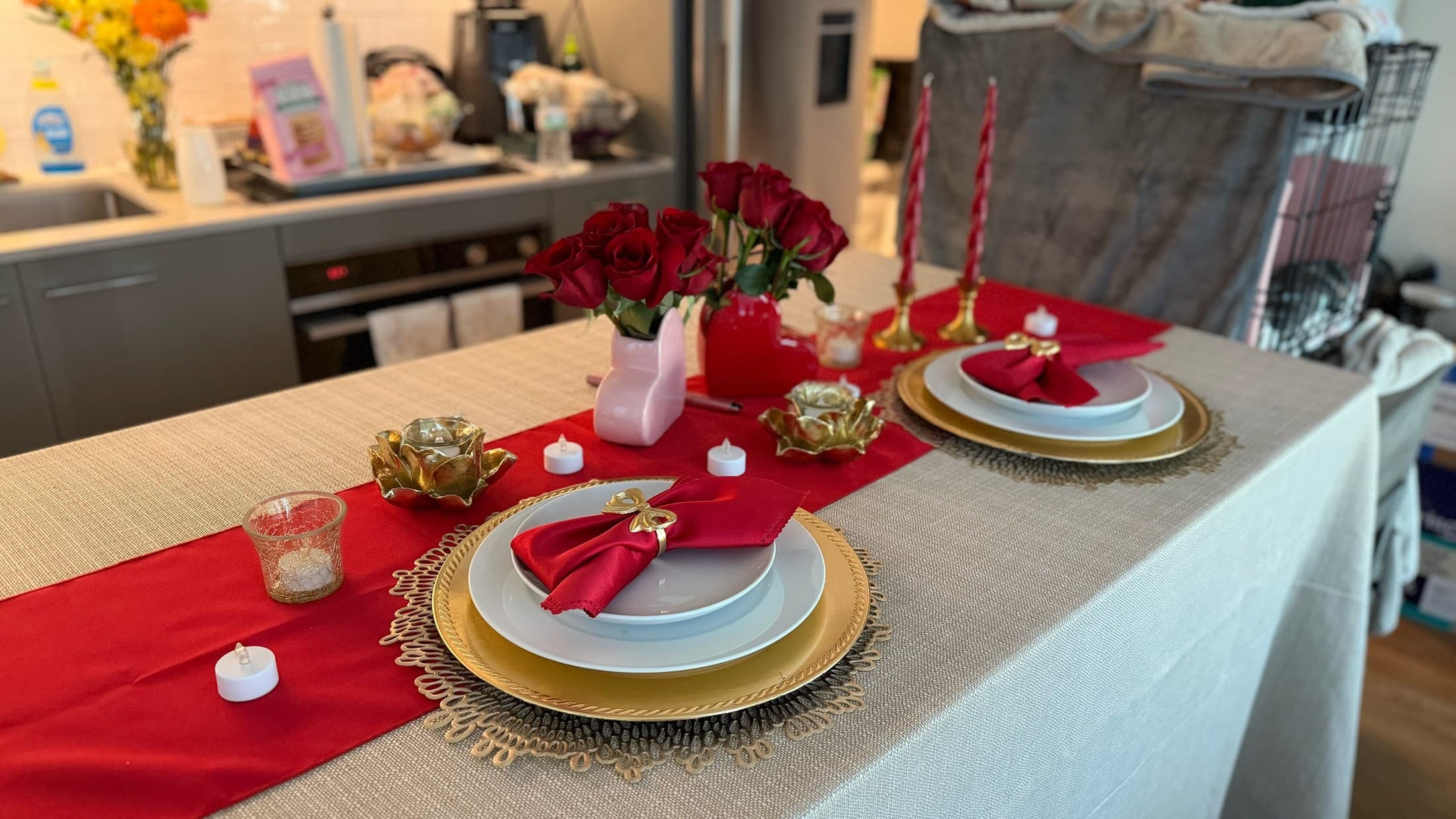 Red and gold holiday place setting with roses, candles, gold charger, and folded napkin.